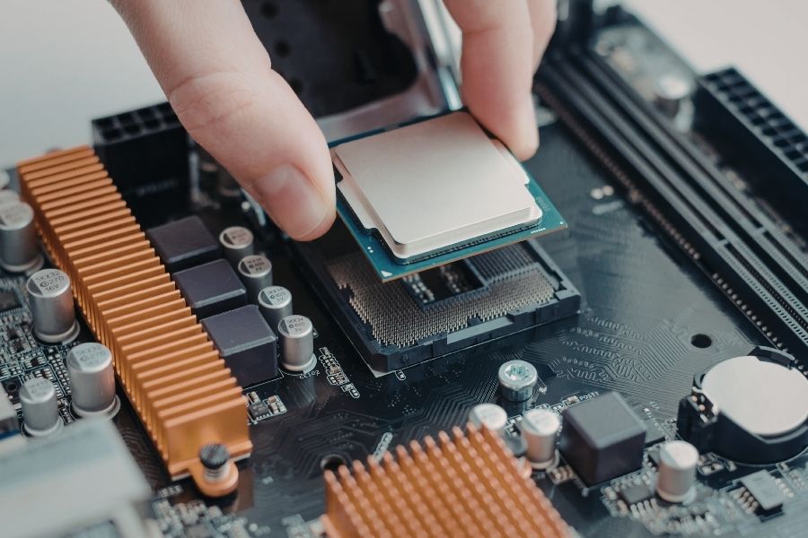 Des doigts installant avec précision un processeur sur une carte mère, étape centrale du débat SSD ou processeur pour optimiser un ordinateur.