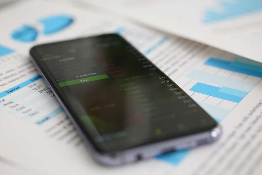 Un smartphone posé sur des documents statistiques pour illustrer l'empreinte carbone numérique.