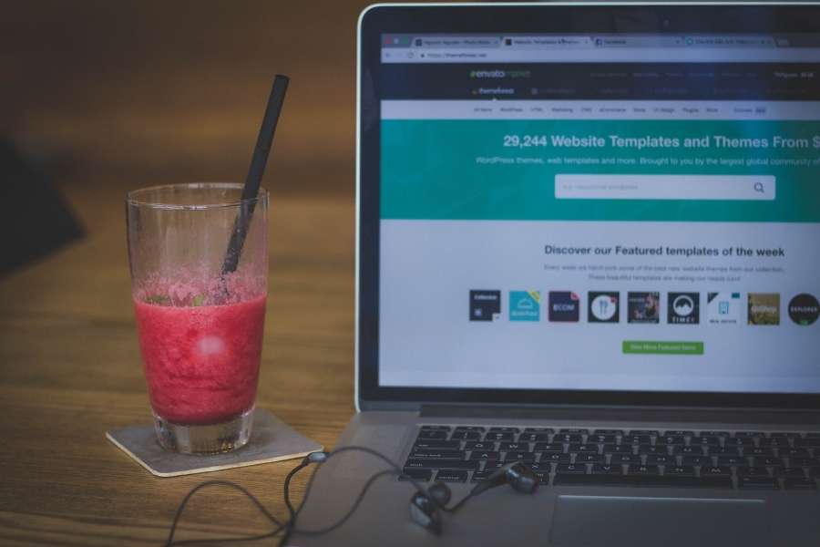 Un ordinateur portable affiche des modèles pour la création d'un site internet professionnel sur une table en bois.